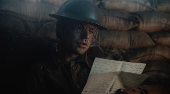 A soldier in a helmet sits in a dark trench reading a handwritten letter.
