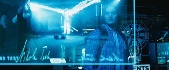 A person in a blue plaid shirt reflected in glass with a glowing blue light and technical diagrams.