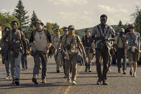 A group of people in vintage-style clothing walking together down a paved road.