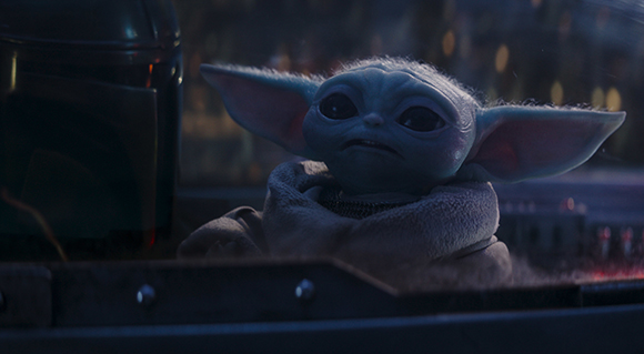 A small, green creature with large pointed ears and large dark eyes looking forward.
