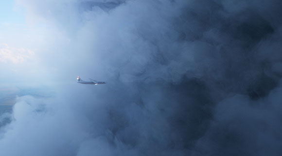 A small airplane flying through a vast expanse of thick, blue-tinted clouds.