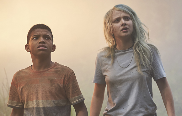 A young boy in a striped shirt and a blonde woman in a grey t-shirt look upward with worried expressions.