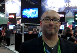 A man with glasses and a goatee wearing a black blazer in a convention center.