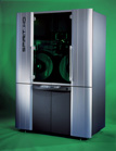 A silver and black computer tower with a transparent side panel showing green internal components.
