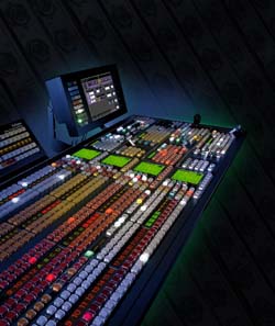 A large digital audio mixing console with numerous glowing buttons, sliders, and a monitor screen.