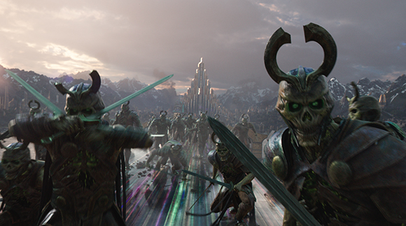Skeletal warriors with horned helmets charge forward toward a tall, glowing spire in a mountainous landscape.