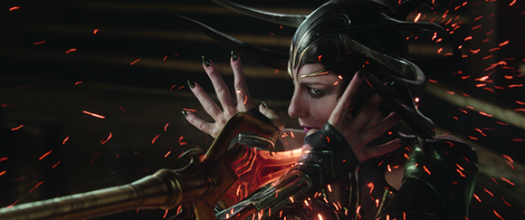 A woman in dark armor and a horned headpiece holds a glowing staff as red sparks fly around her.