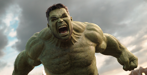 A muscular green humanoid creature with a wide-open mouth roaring against a cloudy sky.