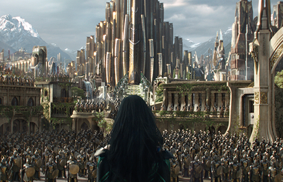 A person with long dark hair overlooks a massive army facing a towering golden city and snowy mountains.