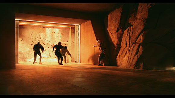 Silhouetted figures run away from a bright explosion inside a large, dimly lit stone structure.