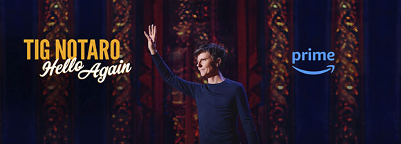 Tig Notaro stands on a dark stage with one arm raised, next to the Amazon Prime logo.