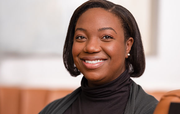 A smiling Black woman with short dark hair wearing a dark turtleneck sweater.