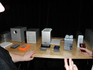 Various computer hardware components and external storage devices are arranged on a wooden table.