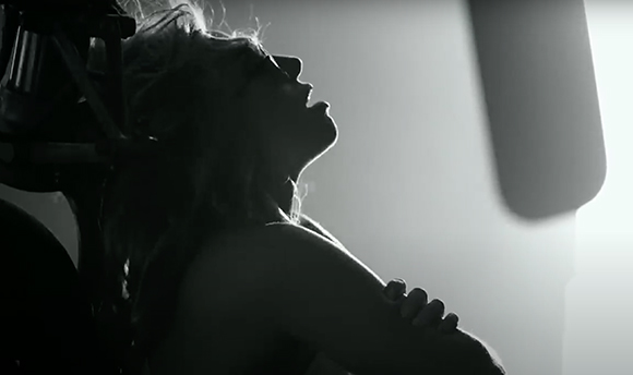 Black and white silhouette of a person with long hair tilting their head back toward a bright light.