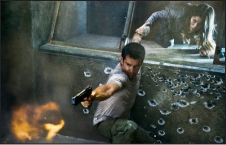 A man in a white shirt aims a pistol in a room filled with bullet holes as a woman reaches down to him.