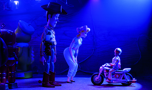 Toy cowboy, cowgirl, and a toy on a motorcycle under bright blue lighting.