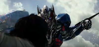 A large, silver and blue metallic robot lunges forward against a bright, cloudy sky.