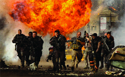 Armed men in tactical gear run through thick smoke and a large orange explosion.