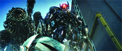 A massive, dark metallic robot stands near industrial pipes and structures under a blue sky.