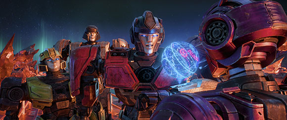 Several large, colorful mechanical robots stand together in a dark environment.