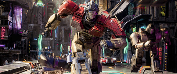 A large red and gold robot runs through a neon-lit futuristic cityscape alongside another robot.