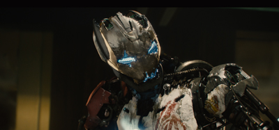 A battle-worn, metallic robotic head with glowing blue eyes and a cracked, white and black armored body.