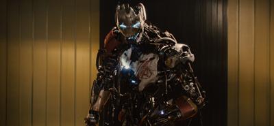 A battle-worn, mechanical humanoid robot with a glowing blue eye and a cracked chest plate.