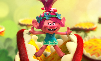 A pink troll with magenta hair and a flower headband stands inside a large, red, toothy plant mouth.
