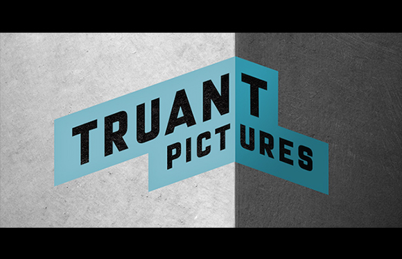 A blue geometric logo for Truant Pictures set against a split light and dark grey textured background.