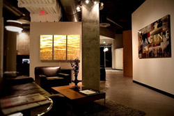 A dimly lit lounge with leather seating, a wooden coffee table, and large abstract artwork on the walls.