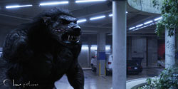 A large, dark, muscular creature with sharp teeth stands in a dimly lit underground parking garage.