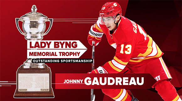 A hockey player in a red jersey with number 13 next to the Lady Byng Memorial Trophy.