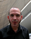 A man with short hair and a goatee wearing a black button-down shirt.