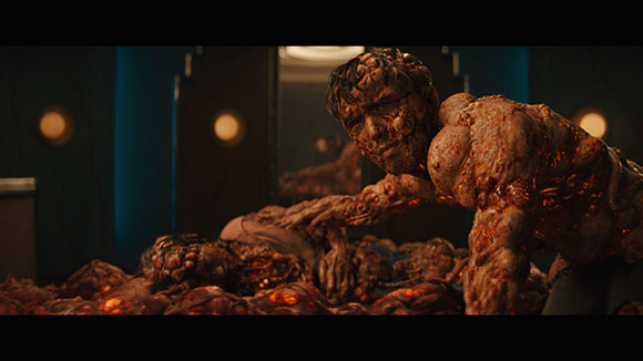A muscular, fleshy humanoid figure with textured skin leans over a pile of organic matter in a dark room.