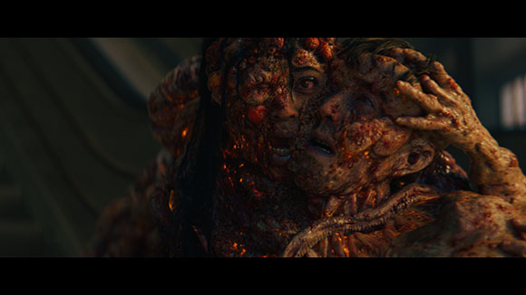 A close-up of a distorted, fleshy mass composed of multiple fused human faces and textures.