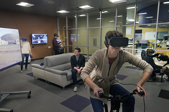 People wearing VR headsets, including one person on a stationary bike, in a modern office or lab.