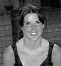 Black and white headshot of a smiling woman with dark hair wearing a dark sleeveless top.