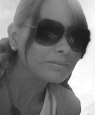 Black and white close-up portrait of a woman wearing large dark sunglasses and a necklace.