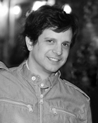 Black and white portrait of a smiling man wearing a collared jacket.