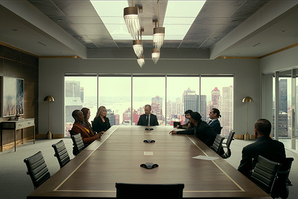 Professionals seated around a long wooden conference table in a modern boardroom with city views.