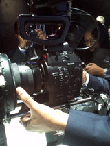 A person's hands holding a large black Canon professional video camera.