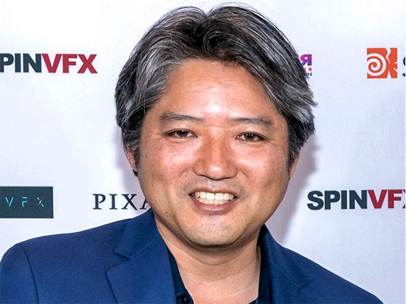 A smiling man with salt-and-pepper hair wearing a blue blazer against a white backdrop.