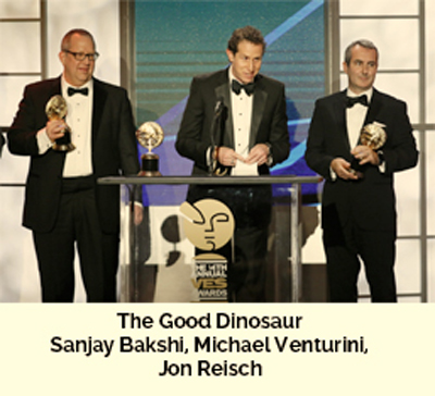 Three men in black tuxedos stand behind a podium holding gold trophies.