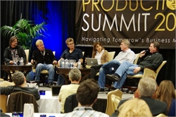 Six people sit in chairs on a stage during a business summit presentation.