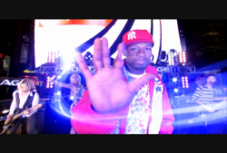 A man in a red jacket and New York Yankees cap holds his palm toward the camera on a brightly lit stage.