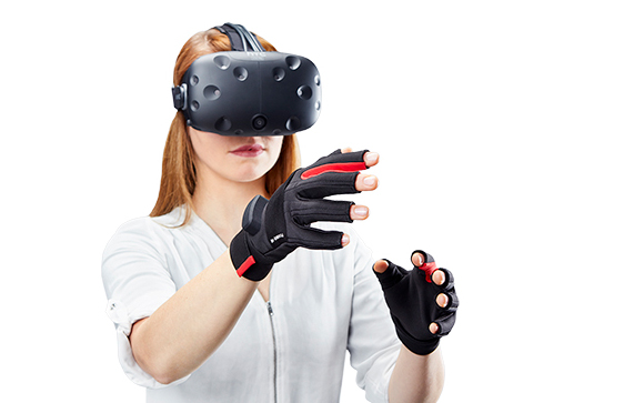 A woman wearing a black VR headset and black and red fingerless haptic gloves against a white background.