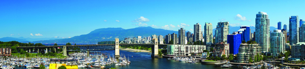 Panoramic view of a city skyline with high-rise buildings, a large bridge, and a marina filled with boats.