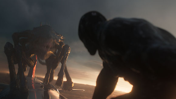 A dark, muscular figure faces a multi-limbed, insectoid creature against a sunset sky.