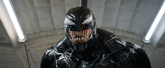 A large, muscular black creature with white eyes and sharp, jagged teeth looking directly at the camera.