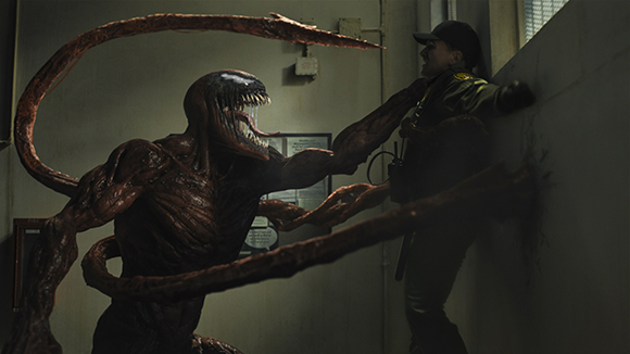 A large red creature with long tentacles and sharp teeth looms over a person in a dark hallway.